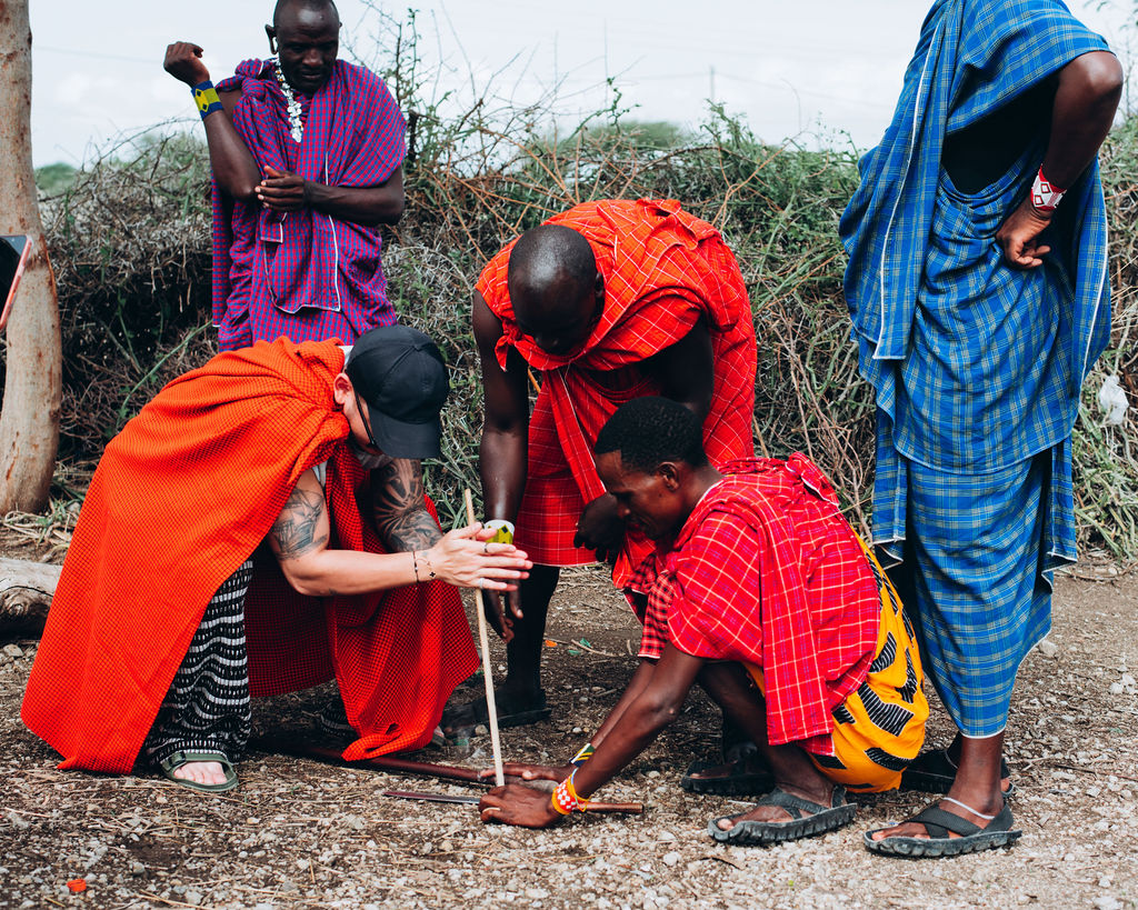 Guest trying traditional fire-making with Maasai hosts