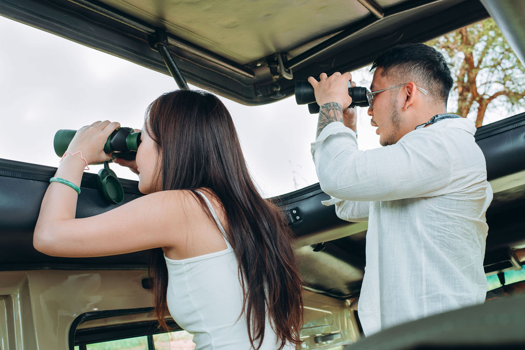 Two guests scanning the bush with binoculars from the roof hatch