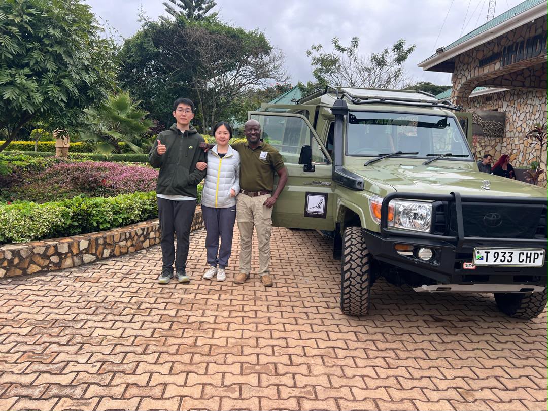 Guests with their guide at a lodge entrance beside the safari vehicle