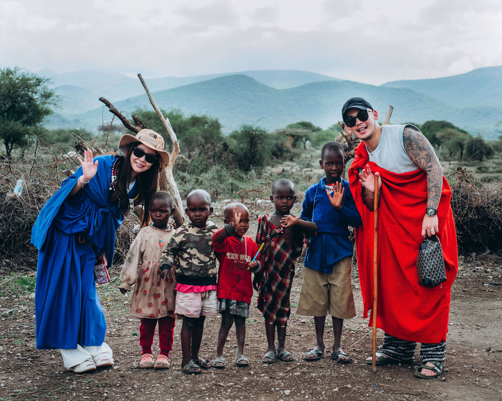 Guests standing with Maasai children outside the village