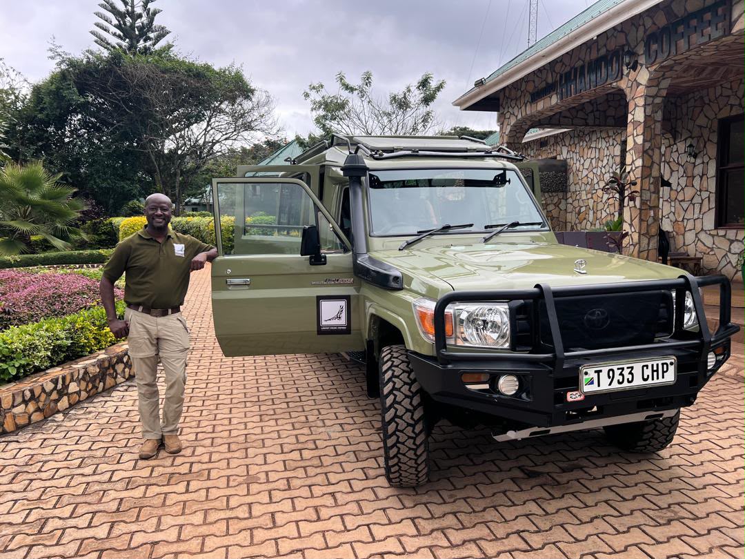 Lappet Faced Safaris guide beside the safari vehicle at a lodge entrance