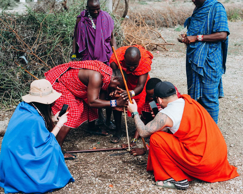 Maasai hosts demonstrating traditional fire-making to guests