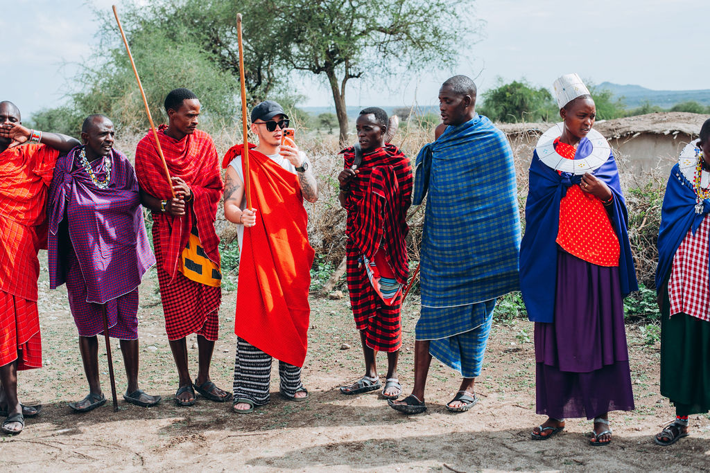 Maasai hosts in red and purple shukas outside their homestead