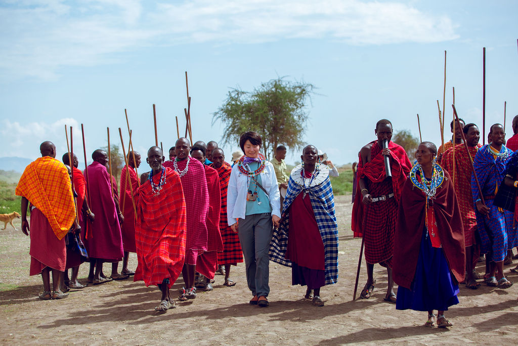 Maasai hosts in a welcome procession with a guest walking among them