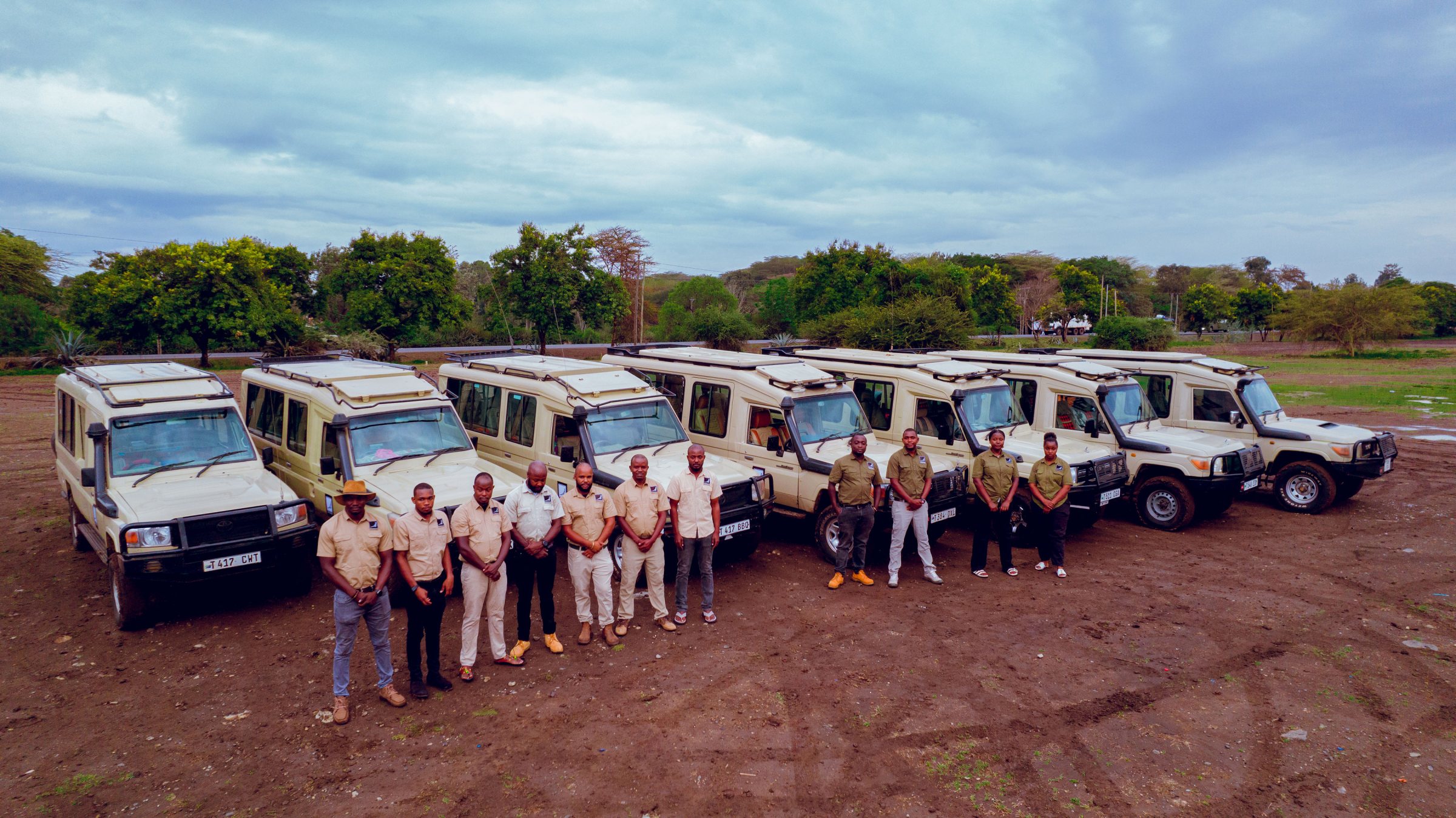 Wide view of the full safari fleet with the guiding team lined up in front