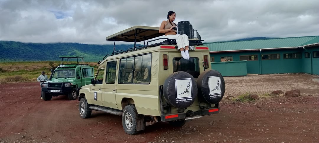 Safari vehicles at a crater descent point with the rim behind