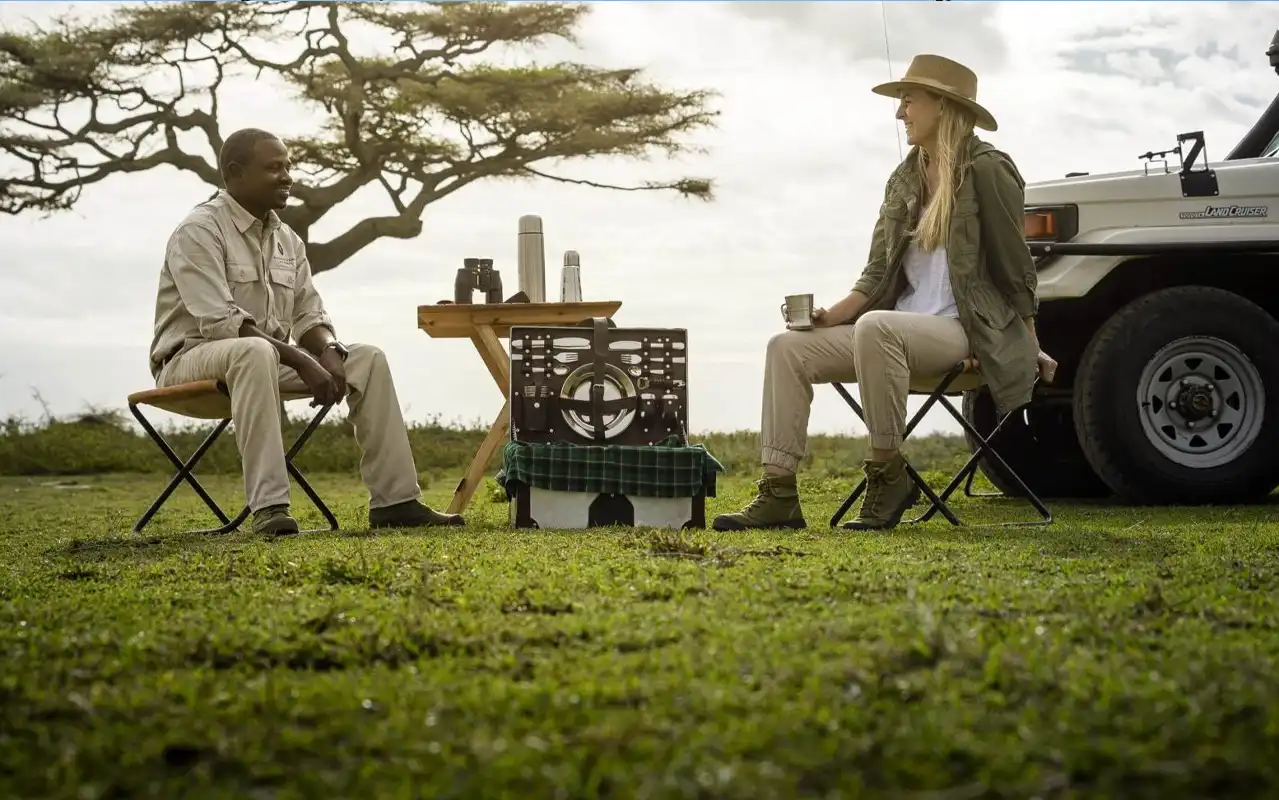 Safari guide planning a route with guests beside a 4x4